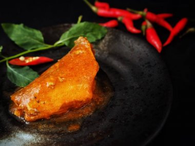 Siyah arka plan üzerine konserve balık kırmızı biber ve yeşil yaprakları