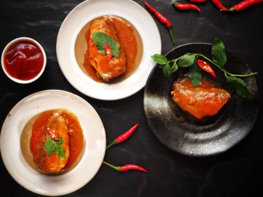 Siyah zemin üzerine kırmızı biber ile konserve balık