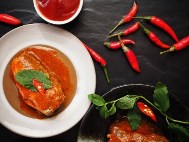 Siyah zemin üzerine kırmızı biber ile konserve balık