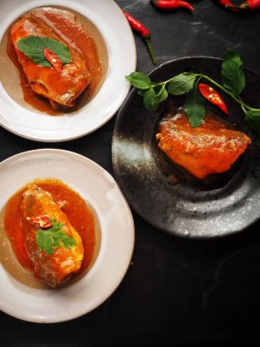 Siyah zemin üzerine kırmızı biber ile konserve balık