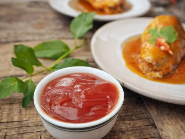 Eski ahşap arka plan üzerinde domates soslu beyaz tabaklarda konserve balık