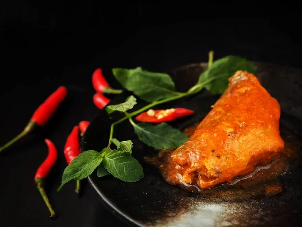 Siyah arka plan üzerine konserve balık kırmızı biber ve yeşil yaprakları