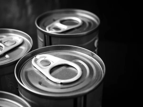 Close view of cans of canned fish on black background
