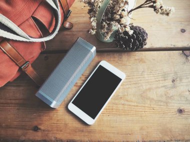 Bluetooth hoparlör smartphone ve çanta ile üstten görünüm ahşap masa üzerinde