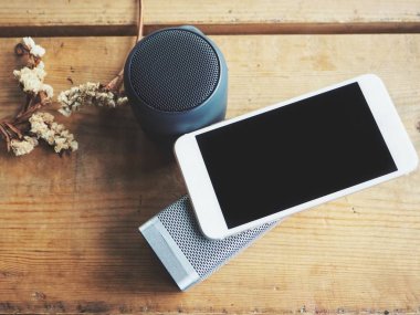 rustik ahşap masa üstünde bluetooth hoparlör ve smartphone üstten görünüm