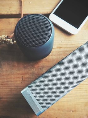 ahşap masa üstünde bluetooth hoparlör ve smartphone üstten görünüm