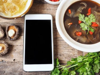 Smartphone ve köpekbalığı yüzgeci ahşap arka plan üzerinde ile Çin çorbası