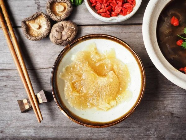 Bowl of traditional Chinese soup with shark fin on wooden background