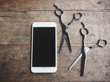 Eski ahşap arka plan üzerinde saç kesme makası ile Smartphone