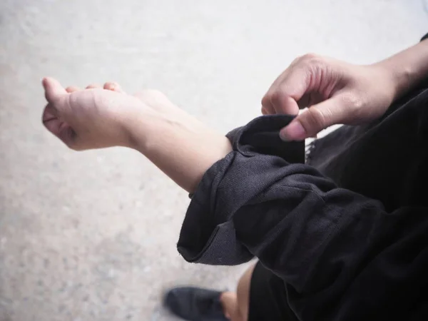 Close view of woman rolling up sleeve on black cotton shirt