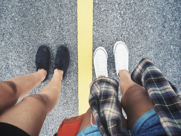 Top view of female feet in stylish sneakers on road