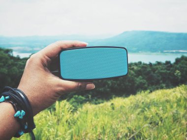 bluetooth hoparlör açık havada tutan kadın görüntüsünü kırpılmış