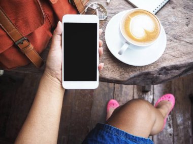 Akıllı telefon ve kahve fincanı çanta kullanan kadın