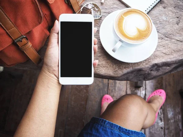Akıllı telefon ve kahve fincanı çanta kullanan kadın