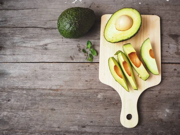 Doğrama Kurulu üzerinde ahşap arka plan üzerinde taze avokado dilimlenmiş