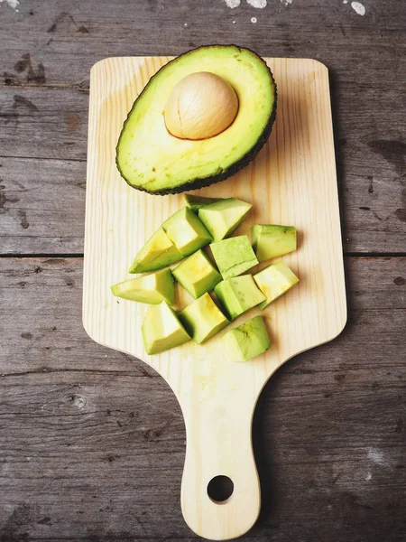 Doğrama Kurulu üzerinde ahşap arka plan üzerinde taze avokado dilimlenmiş