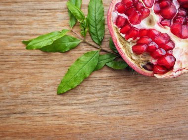 Ahşap zemin üzerine yeşil yaprakları ile taze Olgun kırmızı nar