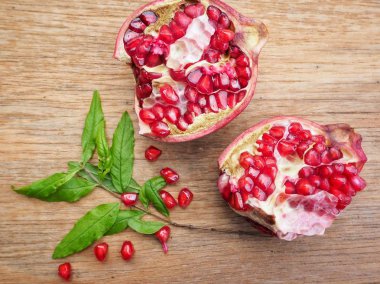 Ahşap zemin üzerine yeşil yaprakları ile taze Olgun kırmızı nar