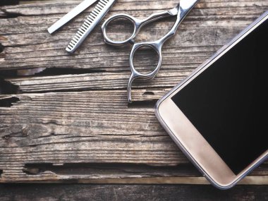 Eski ahşap arka plan üzerinde saç kesme makası ile Smartphone