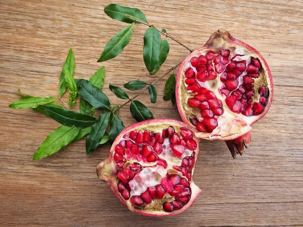 Ahşap zemin üzerine yeşil yaprakları ile taze Olgun kırmızı nar