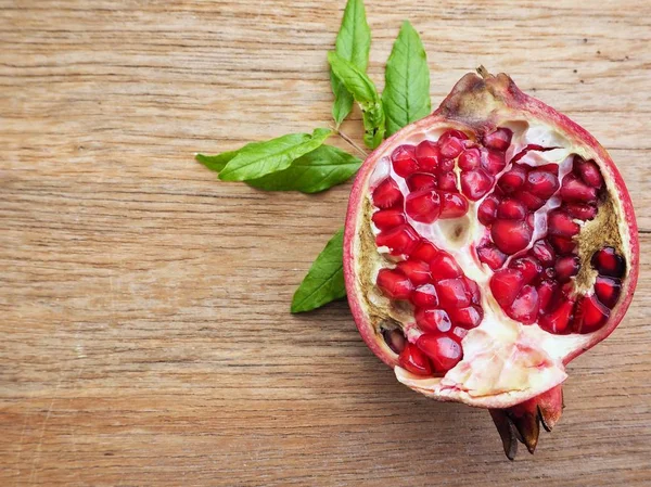 Ahşap zemin üzerine yeşil yaprakları ile taze Olgun kırmızı nar