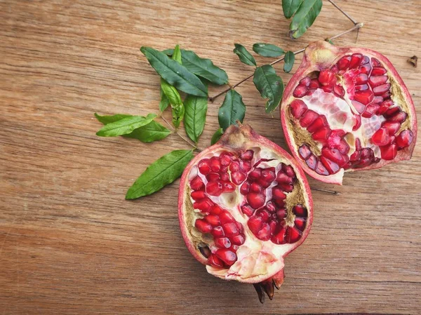 Ahşap zemin üzerine yeşil yaprakları ile taze Olgun kırmızı nar