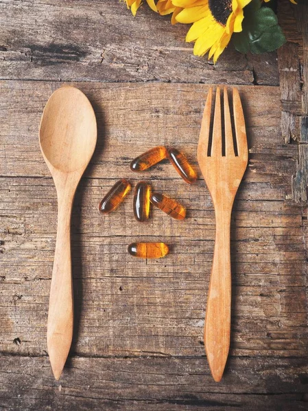 Cod liver oil capsules with fork and spoon — Stock Photo, Image