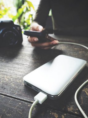 Ahşap masa üzerinde güç banka ile akıllı telefon kullanan kadın