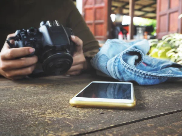 Eski ahşap masa üstünde smartphone ile fotoğraf makinesi kullanan kadın