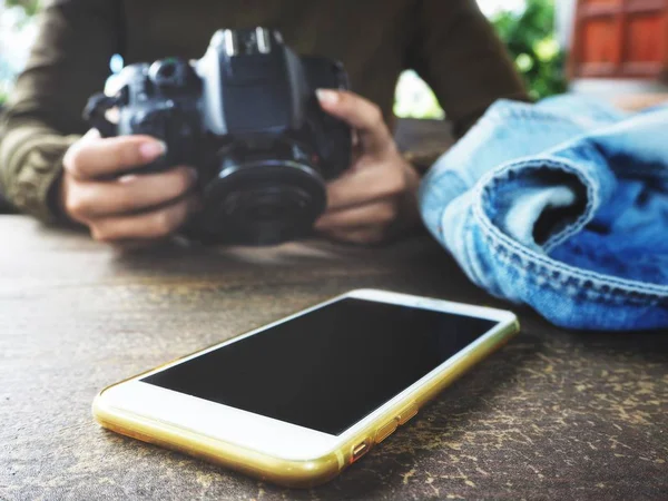 Eski ahşap masa üstünde smartphone ile fotoğraf makinesi kullanan kadın