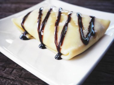 çikolata soslu lezzetli krep beyaz tabakta görmek 