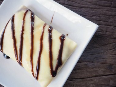çikolata soslu lezzetli krep üstten görünüm beyaz plaka üzerinde 