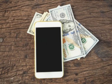 Dolar ile smartphone ahşap arka plan üzerinde yalan yığını