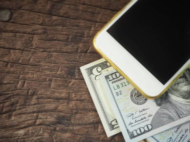 Dolar ile smartphone ahşap arka plan üzerinde yalan yığını