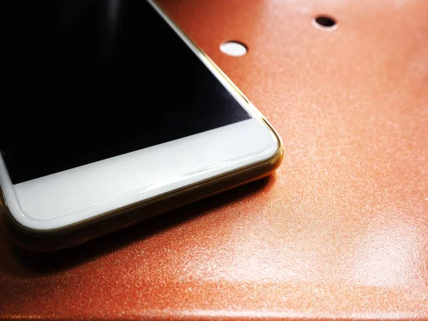 Metal turuncu zemin üzerine beyaz smartphone görünümü Kapat