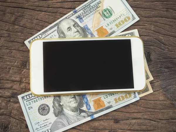 Dolar ile smartphone ahşap arka plan üzerinde yalan yığını