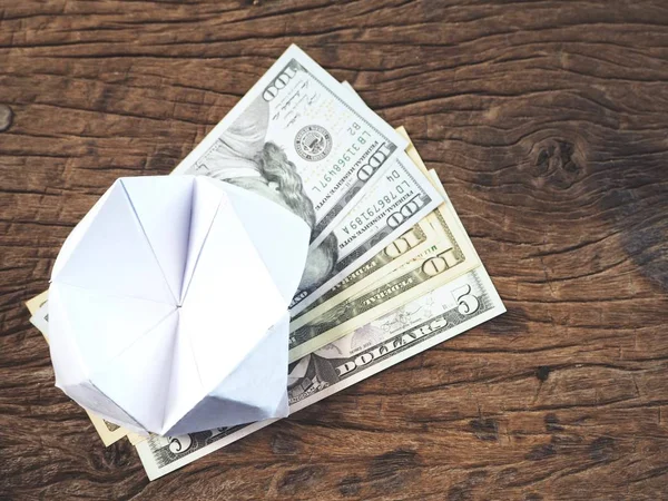 Dollars with paper fortune teller on wooden background