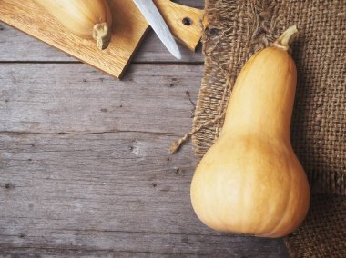 ahşap masa üzerinde butternut kabak, bıçak ve çul üstten görünüm
