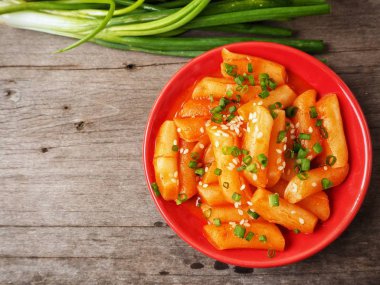 Ahşap arka plan üzerinde taze soğan ile geleneksel Kore yemeği pirinç keki servis