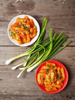 Ahşap arka plan üzerinde taze soğan ile geleneksel Kore yemeği pirinç keki servis