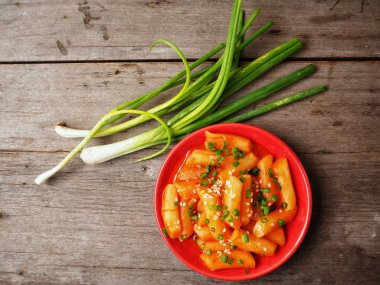 Ahşap arka plan üzerinde taze soğan ile geleneksel Kore yemeği pirinç keki servis