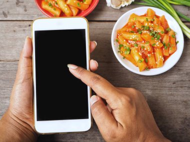 Smartphone ile geleneksel Kore yemeği pirinç keki tutan kadın