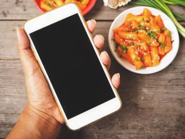 Smartphone ile geleneksel Kore yemeği pirinç keki tutan kadın