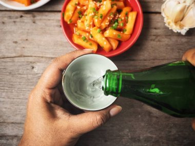 Soju ve geleneksel Kore yemeği pirinç keki Kupası tutan kadın 