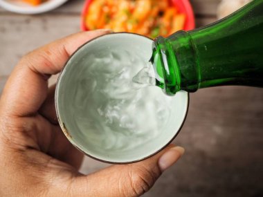 Soju ve geleneksel Kore yemeği pirinç keki Kupası tutan kadın 
