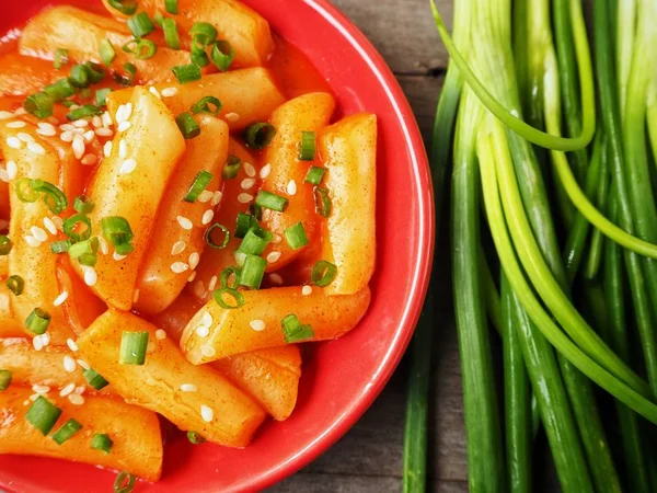 Ahşap arka plan üzerinde taze soğan ile geleneksel Kore yemeği pirinç keki servis