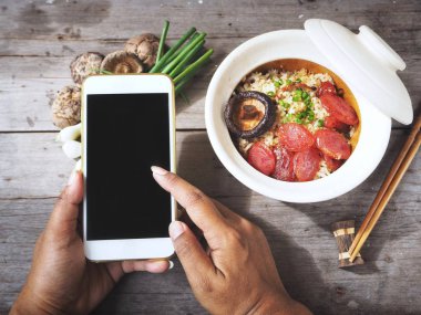 Smartphone soslu kızarmış pilav üzerinde elinde tutan kadın