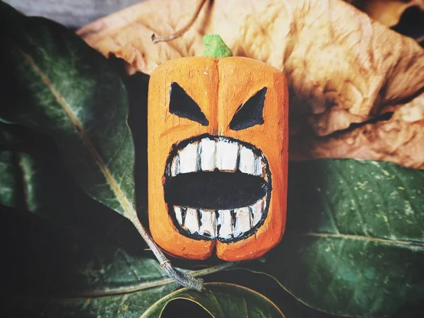 Halloween pumpkin with scary face on wooden background