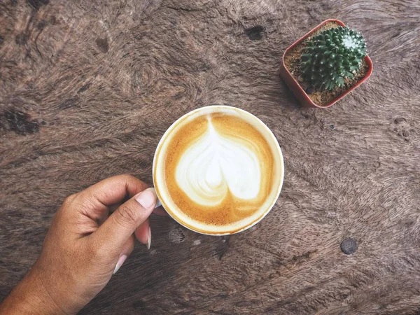 Mujer Sosteniendo Taza Café Latte Arte Sobre Mesa Madera —  Fotos de Stock