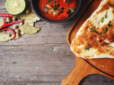 Ahşap arka plan üzerinde Hint naan ekmek ile baharatlı körili çorba servis